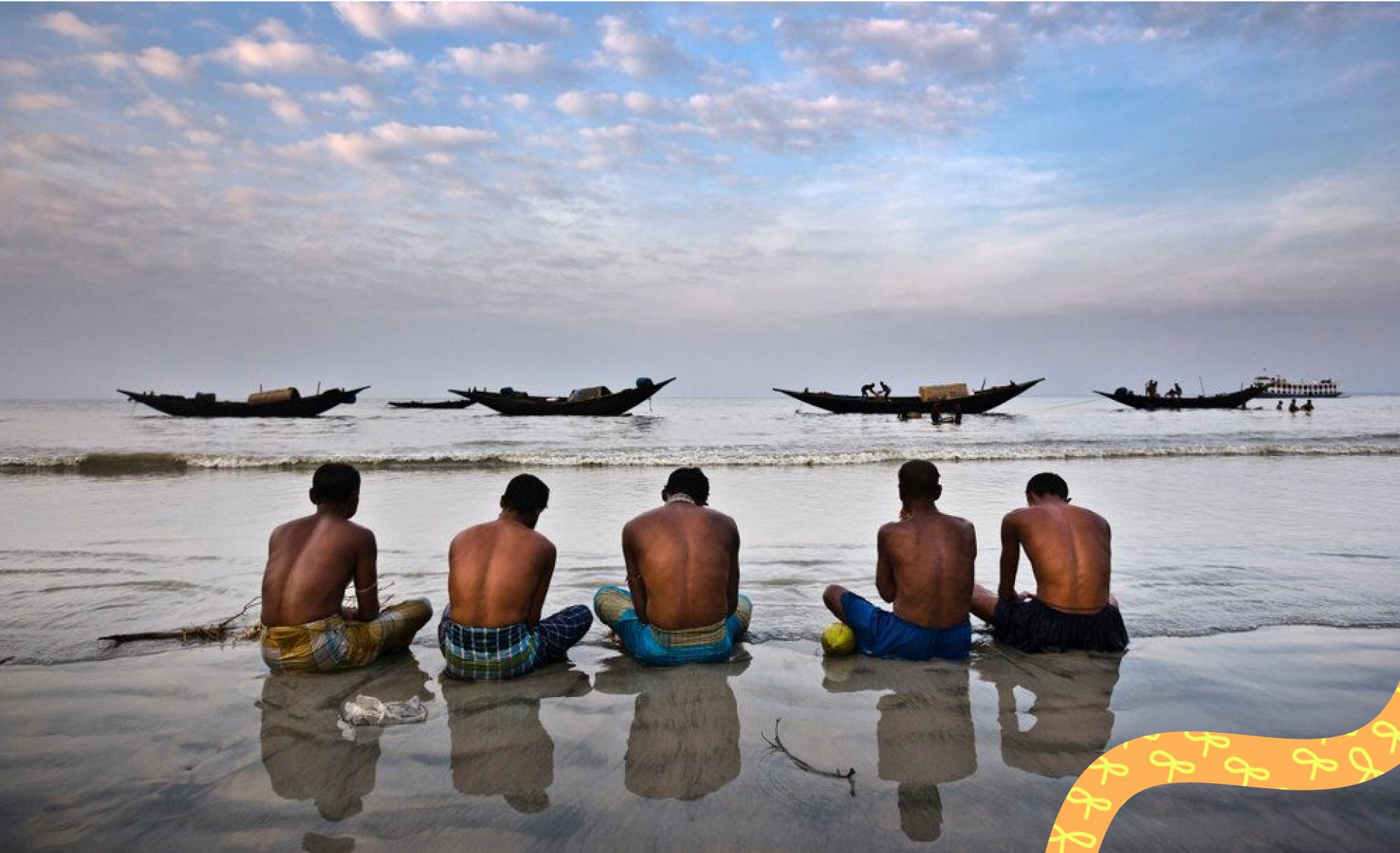 Fishermen sitting on the beach praying for a benevolent sea